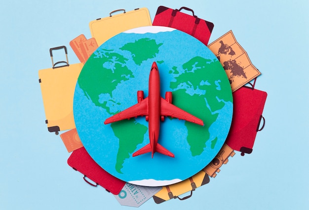 Photo top view earth surrounded by luggage and airplane