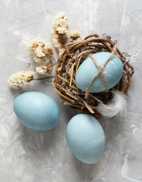 Top view of easter eggs in bird nest with feather and flowers