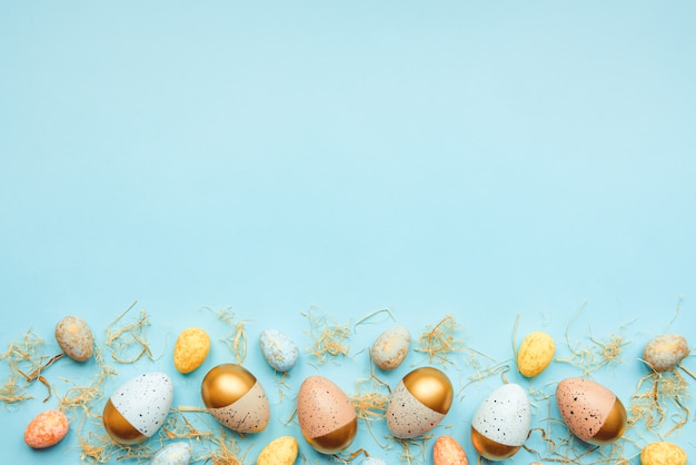 Top view of easter eggs colored with golden paint and different colors. Blue background. Copy space.