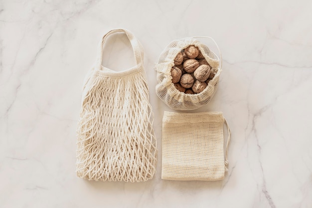 Top view eco bags and walnuts on white marble background