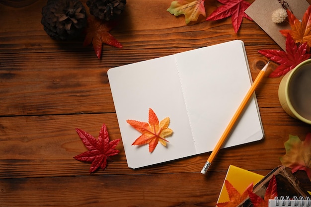 Top view empty notebook coffee cup and maple leaves on wooden background