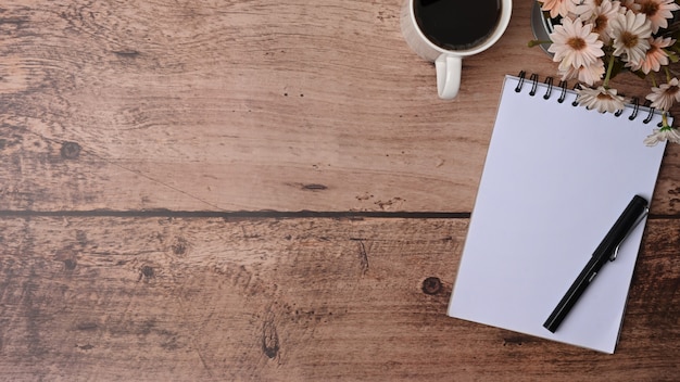 Top view empty notepad, pen and coffee cup on wooden background.