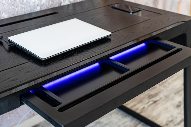 Top view of empty open wooden drawer office table with blue lightning Modern office table with light