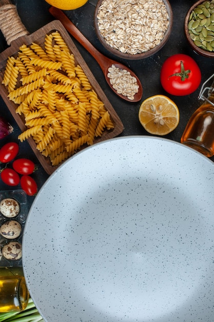 Top view empty plate around eggs tomatoes seasonings and italian pasta on a dark background color vegetable kitchen cuisine food fruit meal