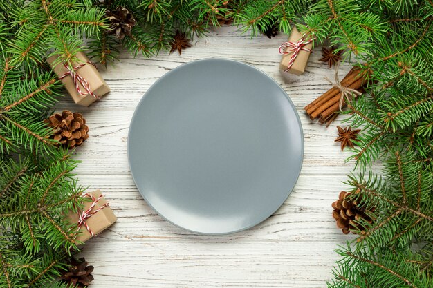 Vista dall'alto. piatto rotondo in ceramica vuota sul tavolo di legno. concetto di piatto cena vacanza con decorazioni di natale