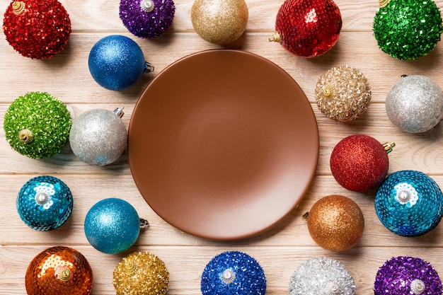 Top view of empty plate surrounded with colorful baubles on wood