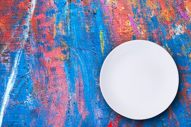 Top view of empty white plate put on colorful table with space for copy.