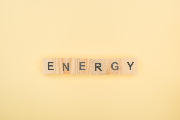 Photo top view of energy lettering made of wooden cubes on yellow background