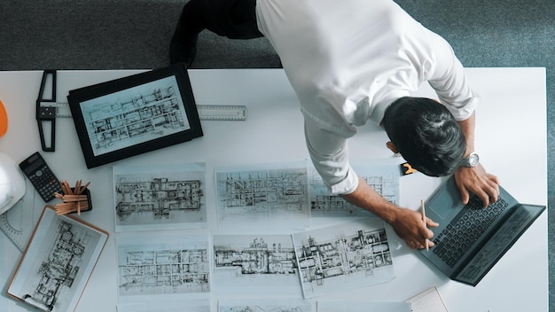 top view of engineer looking at tablet while looking at laptop alimentation