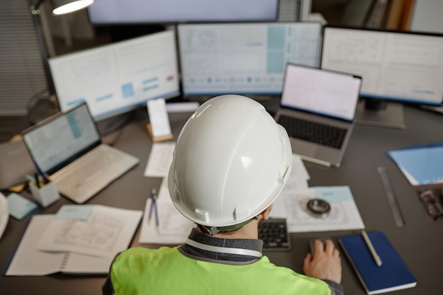 Top view of engineer wearing hardhat and using computer