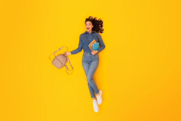 Top View Of Enthusiastic Student Woman Grasping Backpack Yellow Backdrop