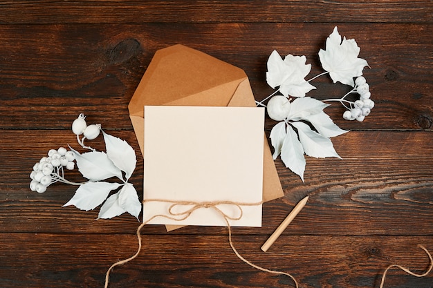 Top view of envelope and blank kraft greeting card with white leaves a