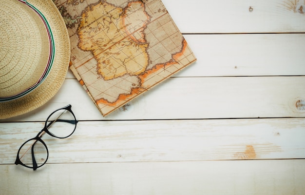 Top view essential travel items.The map passport hat's man  eyeglasses on white  wooden background with copy space.