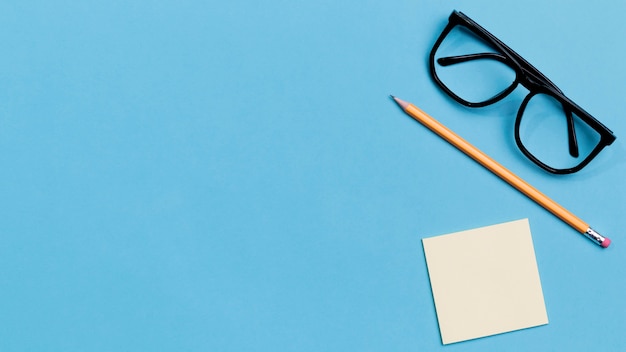 Top view eyeglasses and pencil with copy space