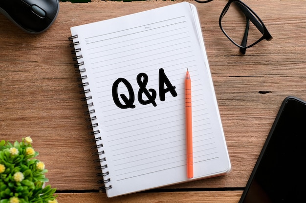 Top view of eyeglasses and wooden board written with text Q and A over wooden background. A business concept.