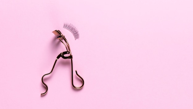 Photo top view of eyelash curler on pink background