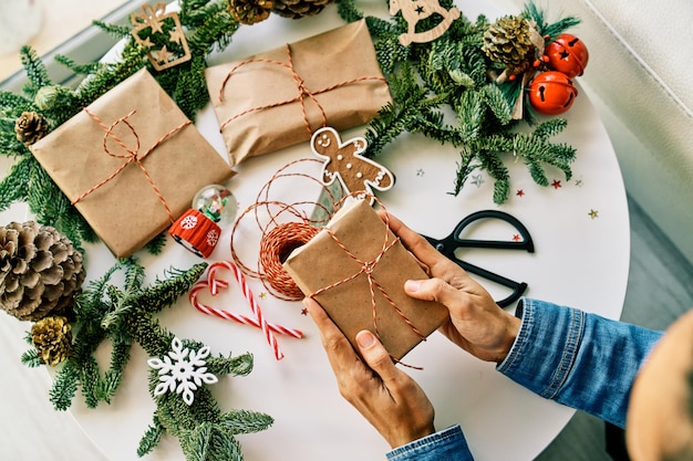 Top view of faceless unrecognizable person putting present on decorated table with Christmas gift boxes