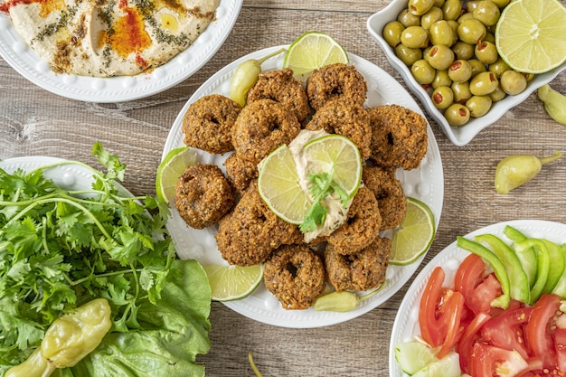 Top view of falafel fries, olives, vegetables and herbs on wooden table