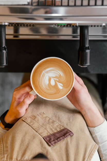 Foto vista dall'alto del barista femminile che tiene tazza di caffè