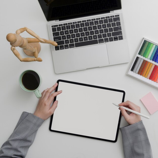 Top view of female designer woking with digital devices and designer supplies