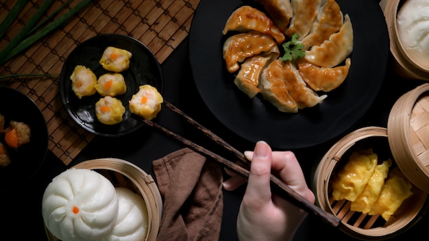 Vista dall'alto di mangiare femminile dim sum con gnocchi, panini e gyoza in ristorante cinese