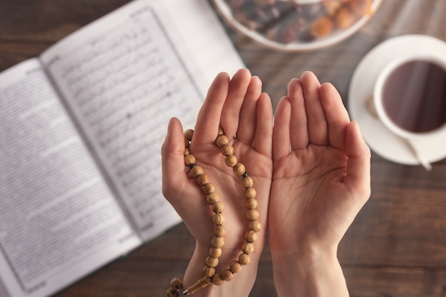 Top view female hand of prayer with wooden beads in sunlight