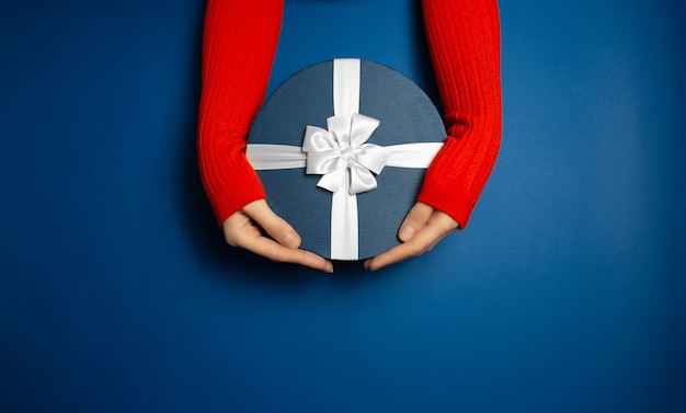 Top view of female hands holding gift box with white bow