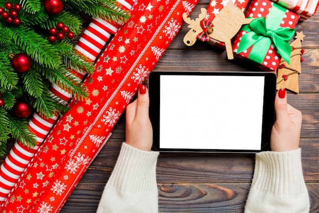 Top view of female hands holding a tablet on wooden christmas