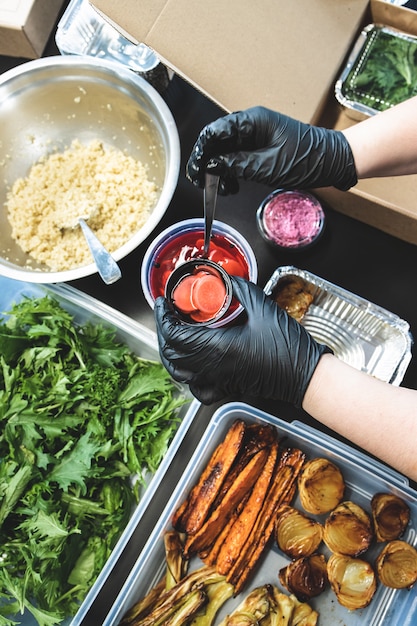 Foto vista superiore delle mani femminili che preparano un'insalata da asporto. consegna