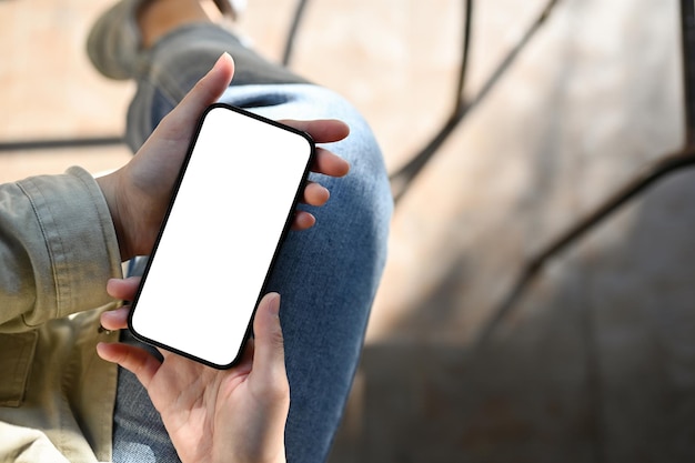 Photo top view a female holding a smartphone white screen mockup over blurred background