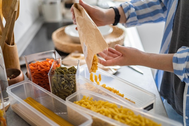 Foto vista dall'alto casalinga femminile che ordina diversi tipi di pasta vegana in scatole di pp