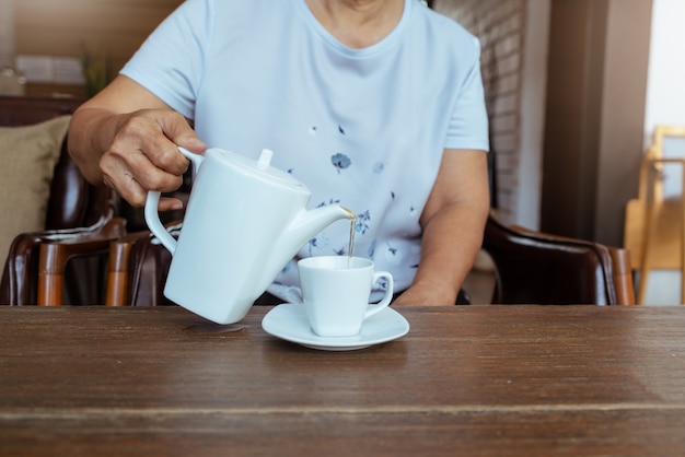 木製のテーブルにお茶を注ぐ女性のトップビュー