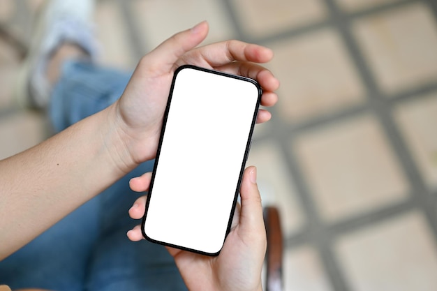 Top view of a female using her smartphone outdoors smartphone white screen mockup