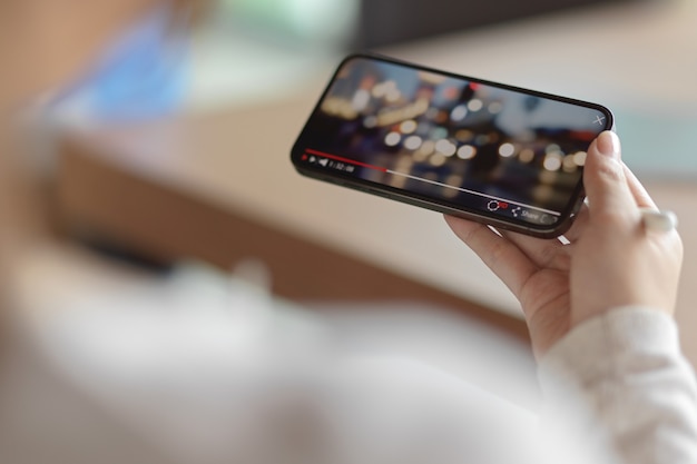 Photo top view of female watching bokeh video on smartphone with blur background