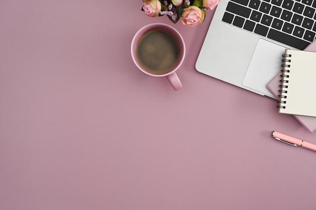 Top view feminine workplace with computer laptop coffee cup notebook and flower pot