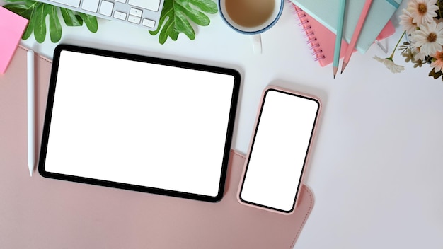 デジタルタブレットスマートフォンノートブックとコーヒーカップを備えたトップビューフェミニンなワークスペース