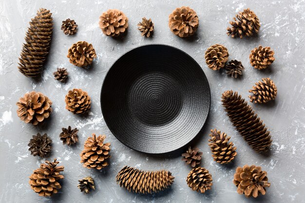 Top view of festive plate with pine cones on cement surface. 