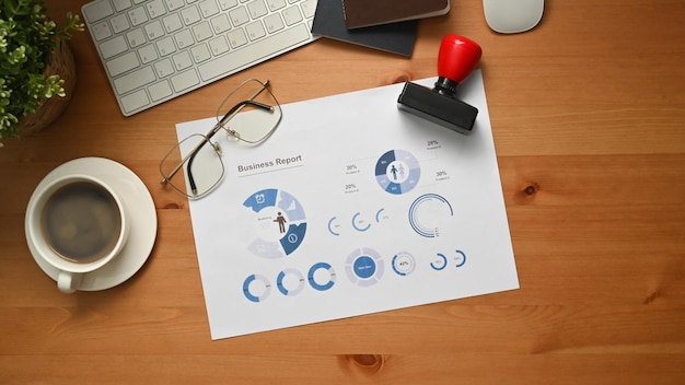 木製の事務机の上の財務書類の眼鏡と一杯のコーヒーの上面図 フラット横たわっていた