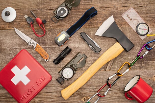 Photo top view of first aid kit and hiking equipment on wooden surface