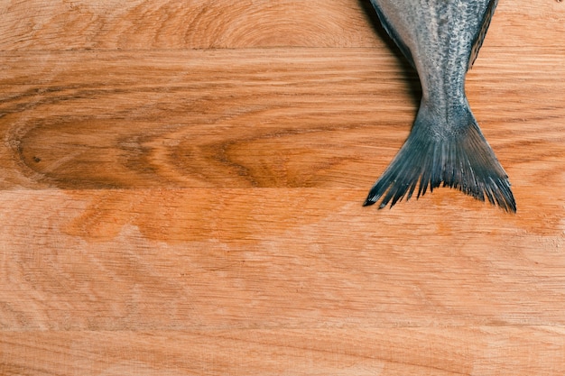 Top view of a fish tail on wooden table on the top of the photo