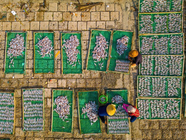 Top view fisherman in fishing villageThey was drying fresh fish on a wooden grid for the market Traditional dried croaker fish drying on racks Lifestyle concept