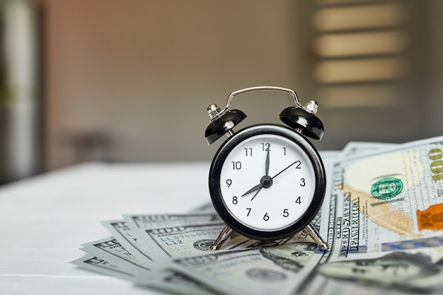 Top view flat lay of Alarm clock and money on white wooden background, Time is money concept