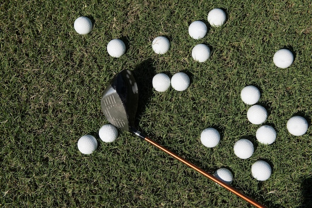 Top view flat lay of golf balls with driver on grass
background