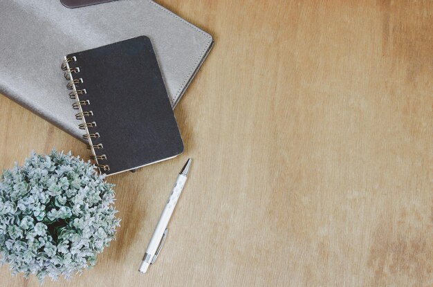 Top view flat lay notebook and flower and pen on wood table.Copy space