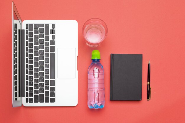 Top view flat lay of office supplies with water bottle