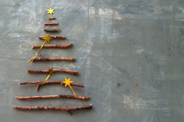 Top view flat lay silhouette of a christmas tree made of wooden twigs decorated with gold stars