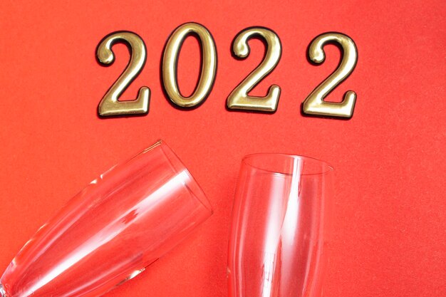 Top view flat new year mockup on red background with numbers, champagne and glasses. Close-up. New Year 2022, with copy space