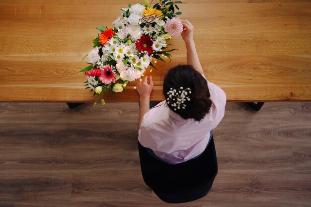 사진 직장의 탑 뷰 플로리스트는 집에서 led 조명으로 장식하는 다른 꽃의 패션 현대적인 구성을 만드는 예쁜 젊은 갈색 머리 여성