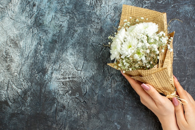 Vista dall'alto bouquet di fiori in mani femminili su sfondo scuro copia posto