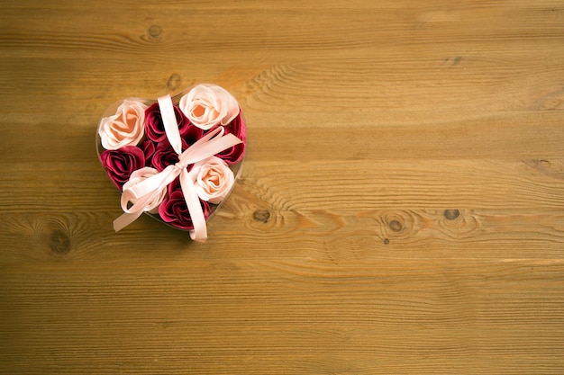 Top view of flowers in a heart box on a wooden table heart box with roses Rose petals in heartshaped box on wooden table